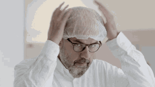a man with glasses and a beard wears a plastic cap