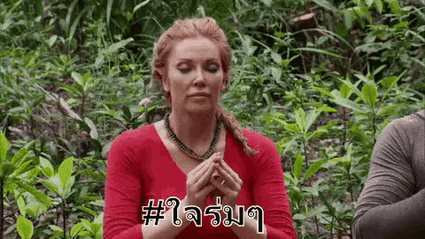 a woman in a red shirt is sitting in the middle of a forest .