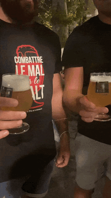 a man wearing a combattri t-shirt holds a glass of beer in his hand