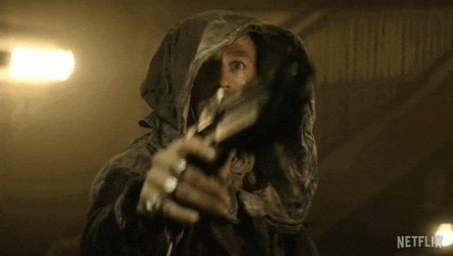 a man in a hooded jacket is pointing a gun at the camera with a netflix logo behind him