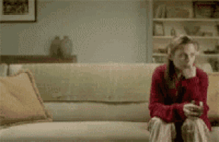 a woman in a red sweater sits on a couch