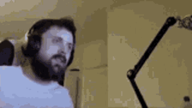 a man with a beard is sitting in front of a microphone wearing headphones .