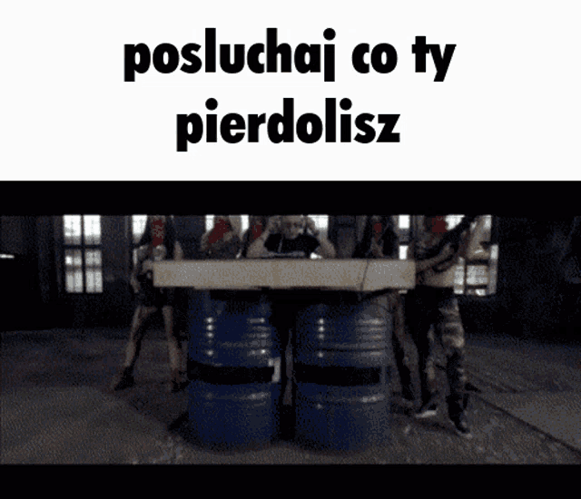 a group of people standing around barrels with the words " posluchaj co ty pierdolisz " on the top