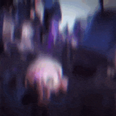 a blurry picture of a crowd of people with purple lights behind them