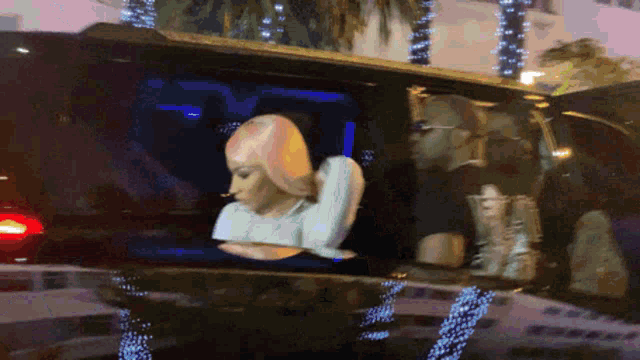 a woman with blonde hair is sitting in a car