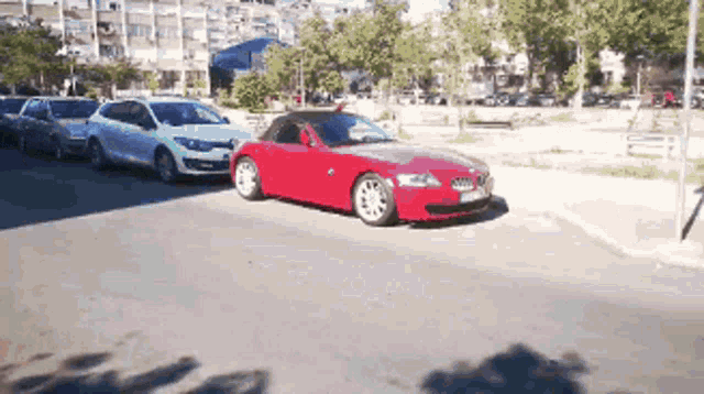 a red car is parked on the side of the road next to other cars