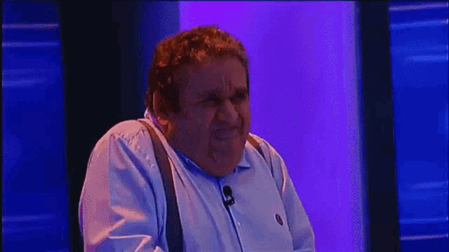 a man with suspenders is making a funny face in front of a blue and red background