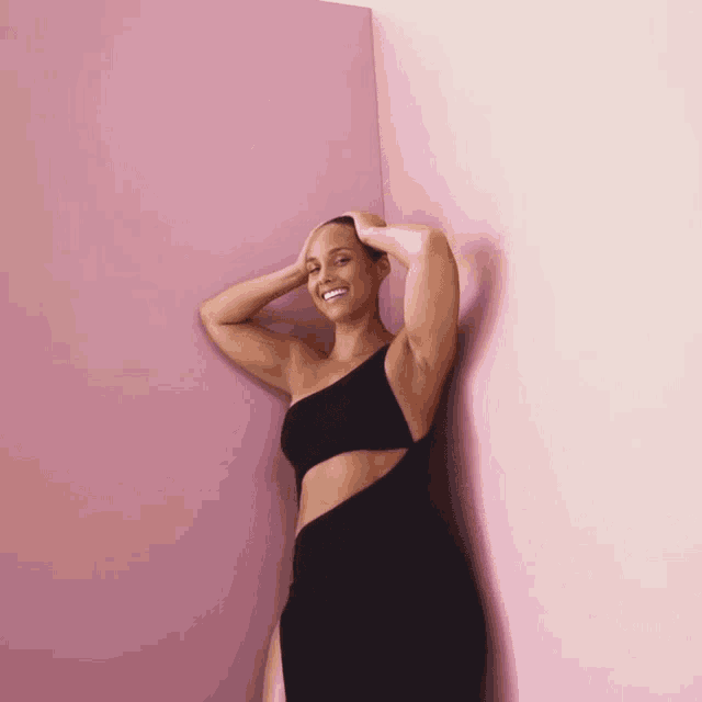 a woman leaning against a pink wall with her hand on her head