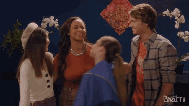 a group of people hugging each other with a brat tv logo in the foreground