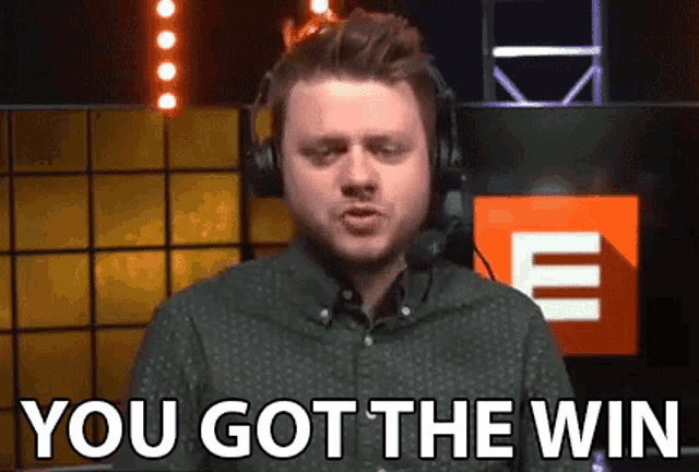 a man wearing headphones is saying `` you got the win '' while standing in front of a screen .