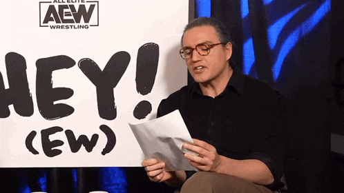 a man reads a piece of paper in front of a sign that says hey