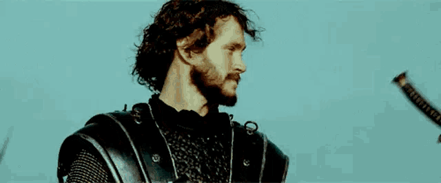 a man with a beard is holding a sword .