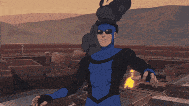 a man in a blue and black superhero costume is holding a fire