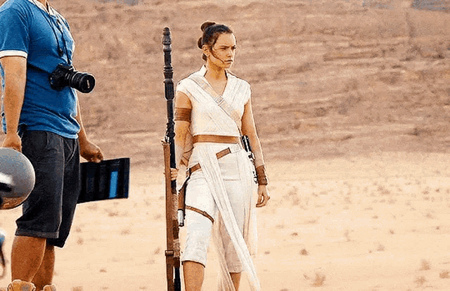 a woman in a white dress is standing in the middle of a desert holding a pole .