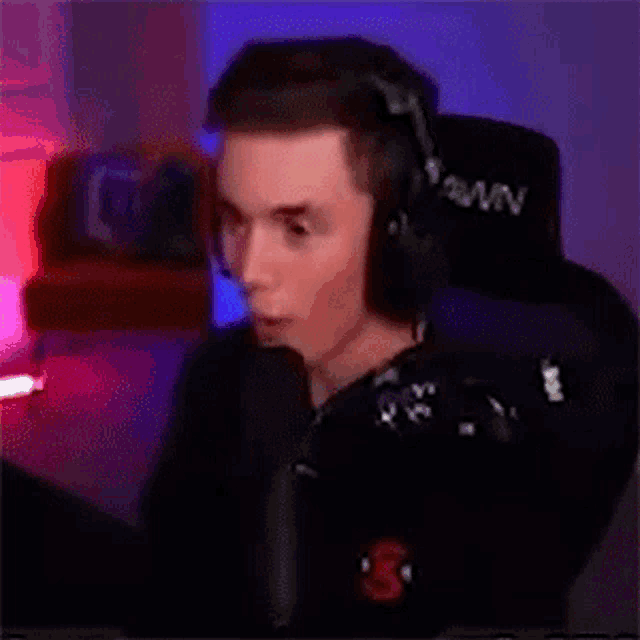 a man wearing headphones is sitting in front of a microphone in a room .