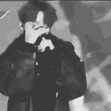 a man is singing into a microphone on stage in a black and white photo .