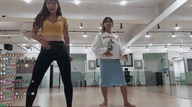 a woman wearing a donald duck sweatshirt stands next to another woman in a dance studio