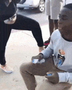 a man is kneeling down on the ground while holding a cell phone .