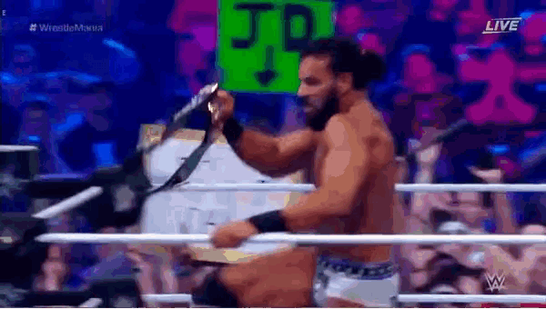 a man is standing in a wrestling ring holding a microphone and a belt .