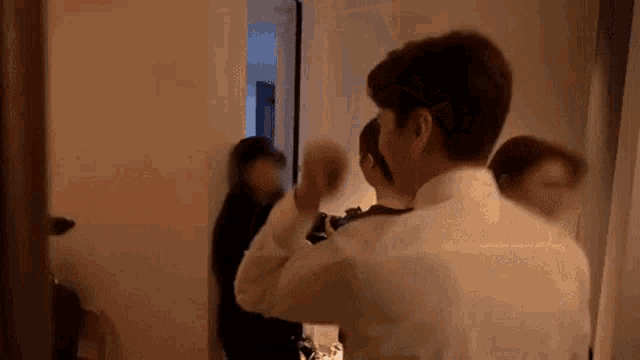 a man in a white shirt is standing next to another man in a room .