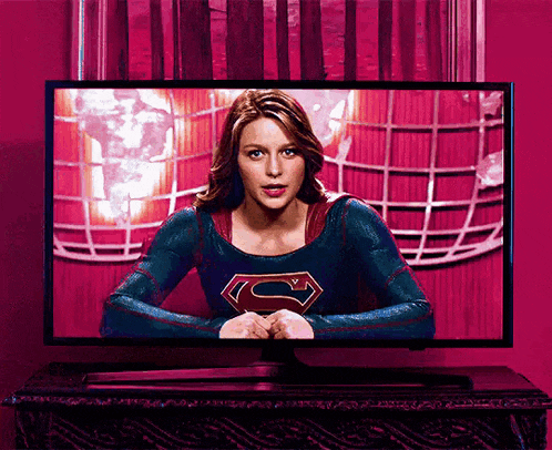 a woman in a superman costume is sitting in front of a television