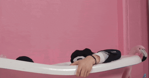 a man dressed as a clown leaning on a railing against a pink wall