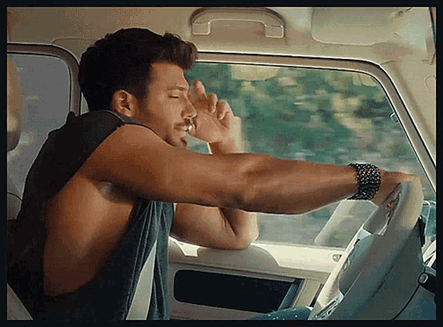 a shirtless man is sitting in a car with his hand on the window