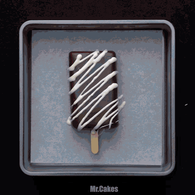 a chocolate bar with white icing on it is in a pan that says mr.cakes on it