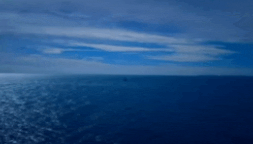a boat is floating on top of a large body of water with a blue sky in the background .