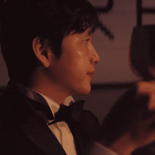 a man in a tuxedo holds a wine glass in his hand