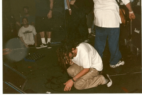 a man with dreadlocks is kneeling down on the floor in front of a marshall amplifier