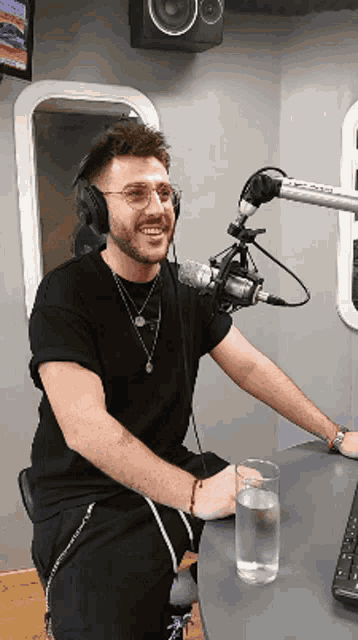 a man sitting in front of a microphone with a glass of water