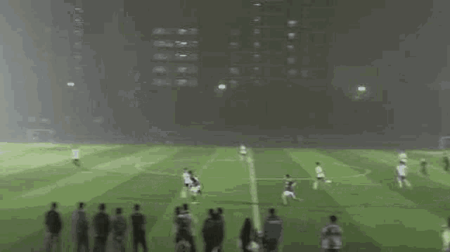 a group of people are watching a soccer game at night on a soccer field .