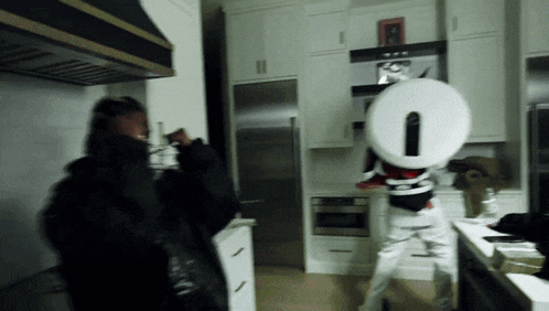 a person standing in a kitchen holding a large white number 0