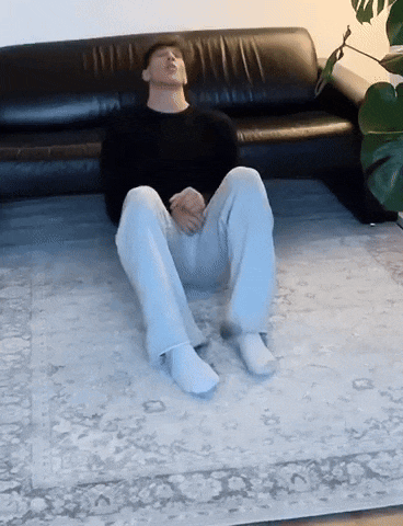a man is sitting on a rug in front of a couch .