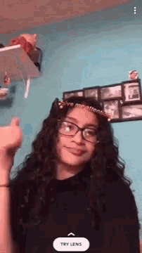 a girl with curly hair and glasses is wearing a headband with the words `` give me attention '' on it .