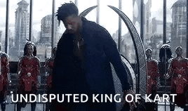 a man in a black suit is standing in front of a throne with the words `` undisputed king of kart '' .