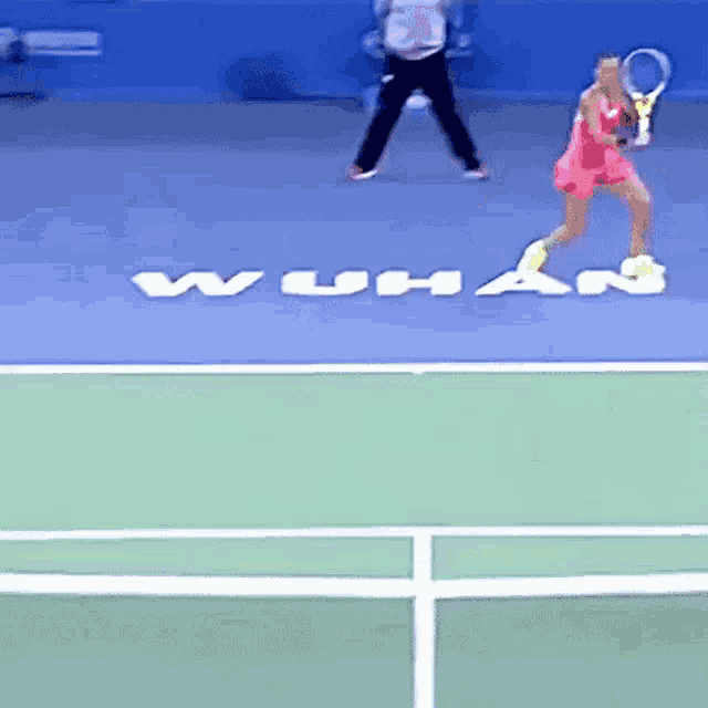 a woman is holding a tennis racquet on a tennis court with the word wuha written on the court