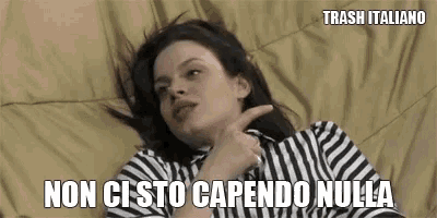 a woman in a striped shirt is laying on a bed and pointing at something .