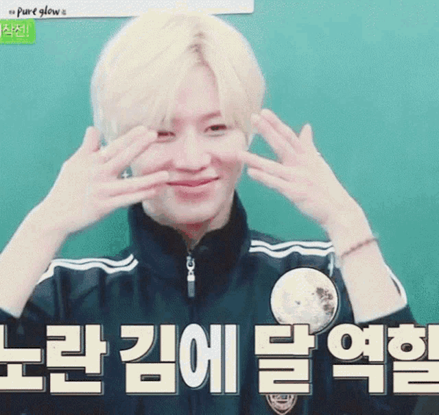 a young man with blonde hair is making a funny face with his hands on his face .