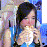 a woman wearing a blue top is eating a sandwich