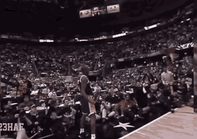 a basketball player stands on a court in front of a crowd with the word 23haf on the bottom