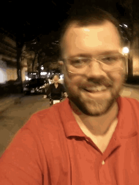 a man wearing glasses and a red shirt smiles for a picture