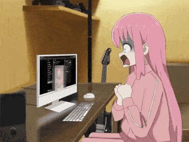 a girl with pink hair is sitting in front of a computer monitor