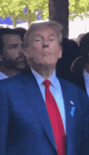 a man in a blue suit and red tie is making a funny face