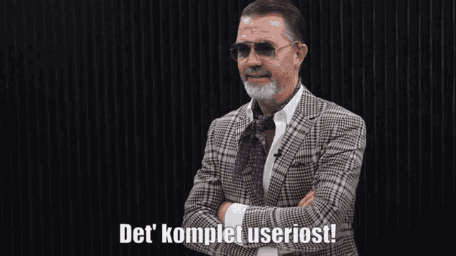 a man wearing sunglasses and a suit says det komplet useriost