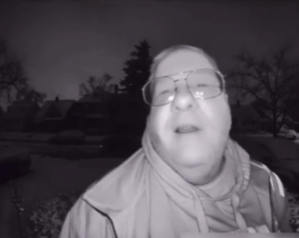 a man with glasses and a scarf around his neck looks at the camera