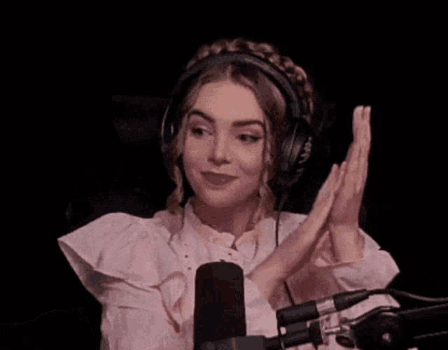 a woman wearing headphones and a pink shirt is sitting in front of a microphone .