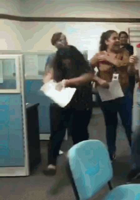 a group of people are standing in a room and one of them is holding a piece of paper