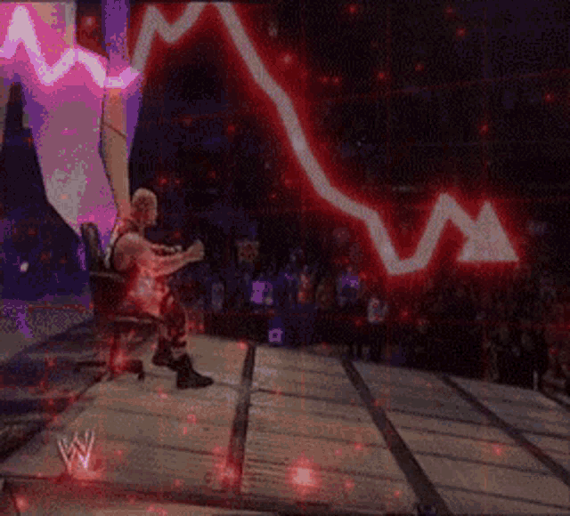 a wrestler is sitting on a stage in front of a wall with a graph on it